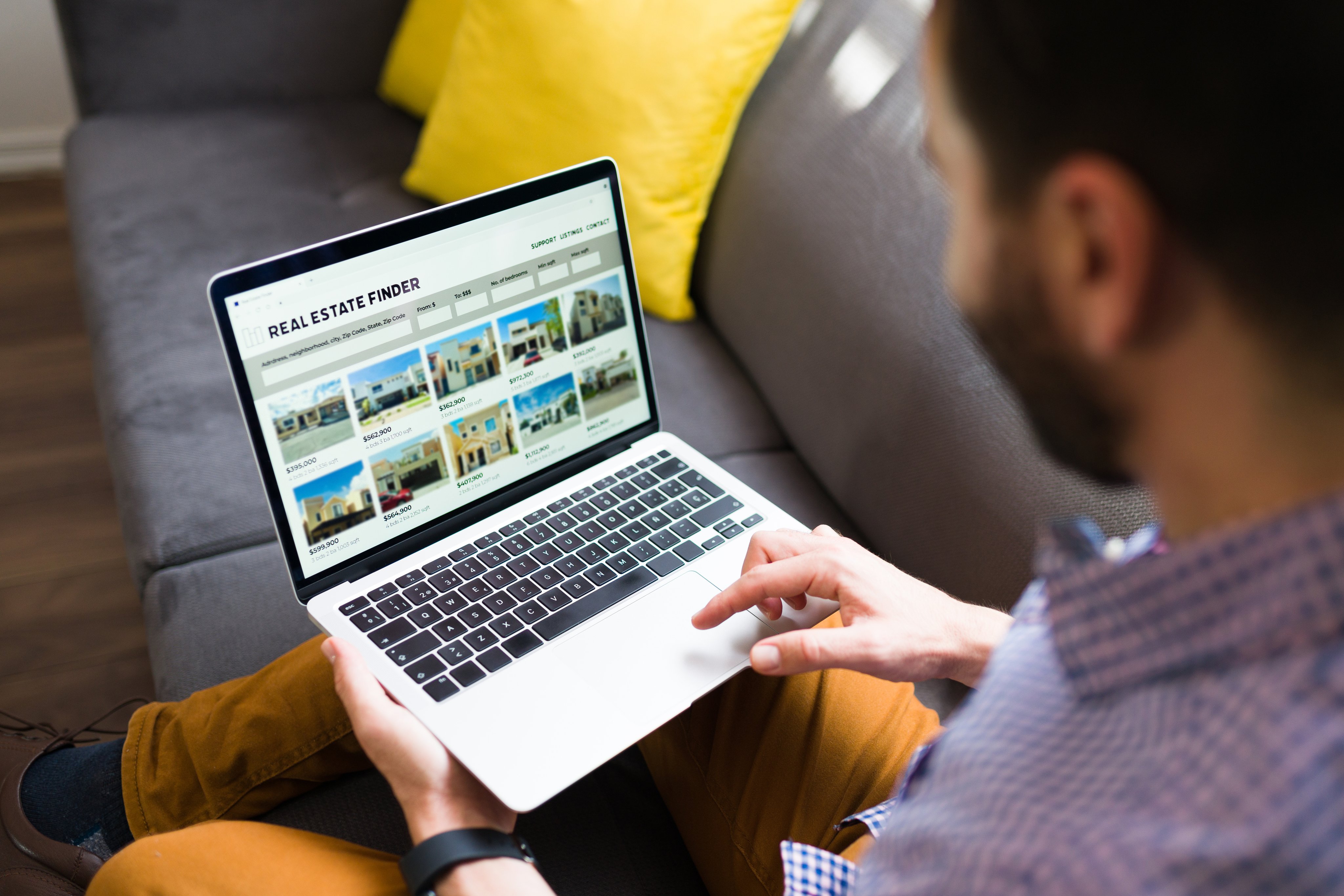 A person browsing home listings with prices on a laptop.