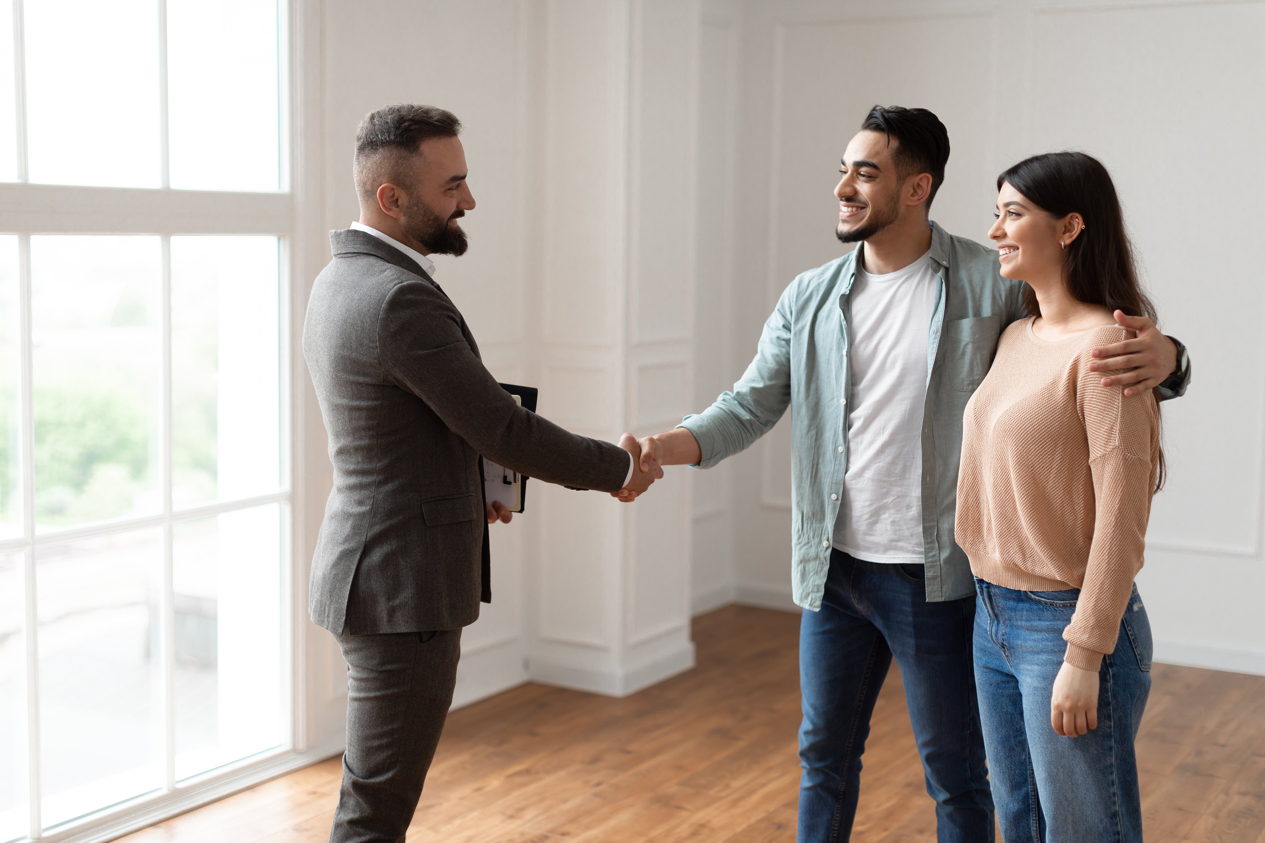 A real estate agent shaking hands with a couple during a home showing