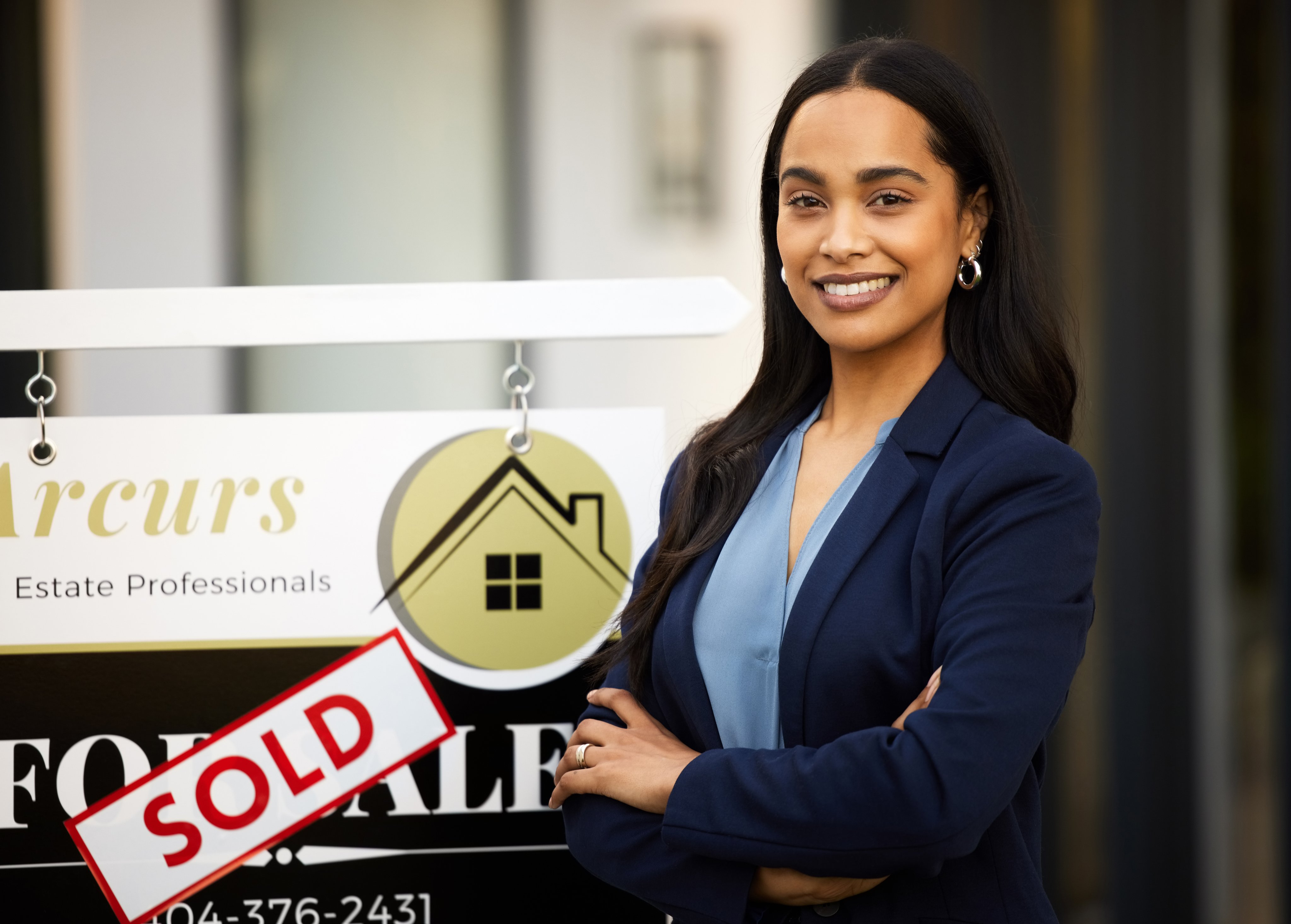 Confident real estate agent smiling in front of a sold sign