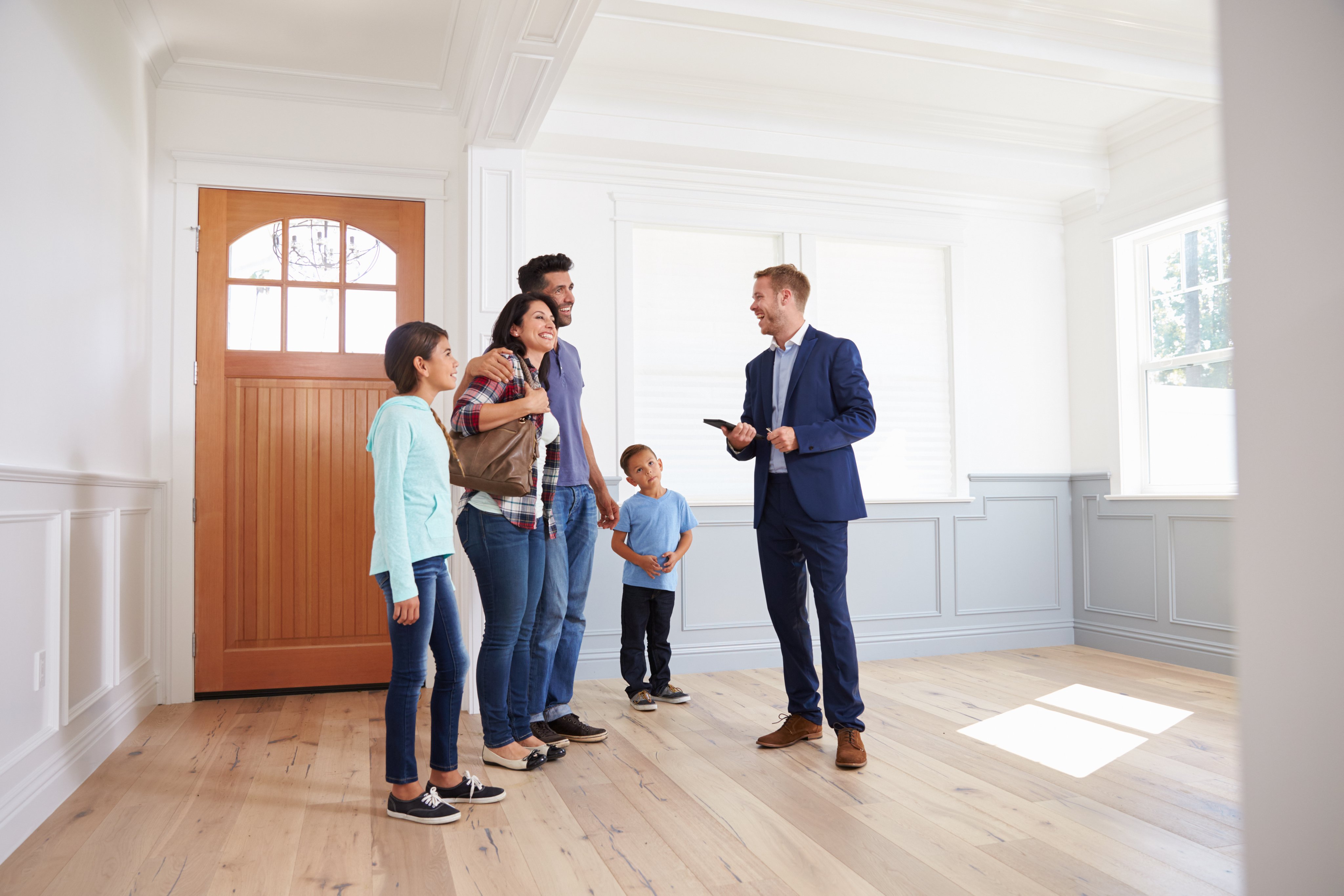 Real estate agent touring a family through a home with light hardwood floors