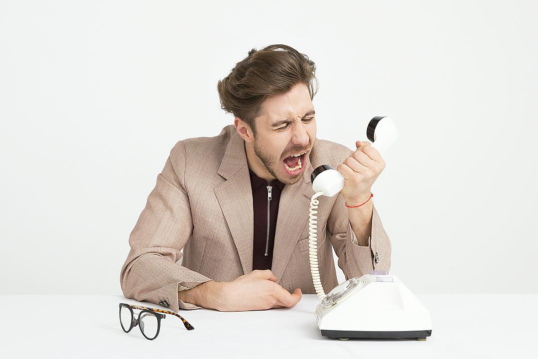 A caller reacting with visible frustration on a live phone call, the moment a delayed or broken response makes them talk over the agent or hang up.