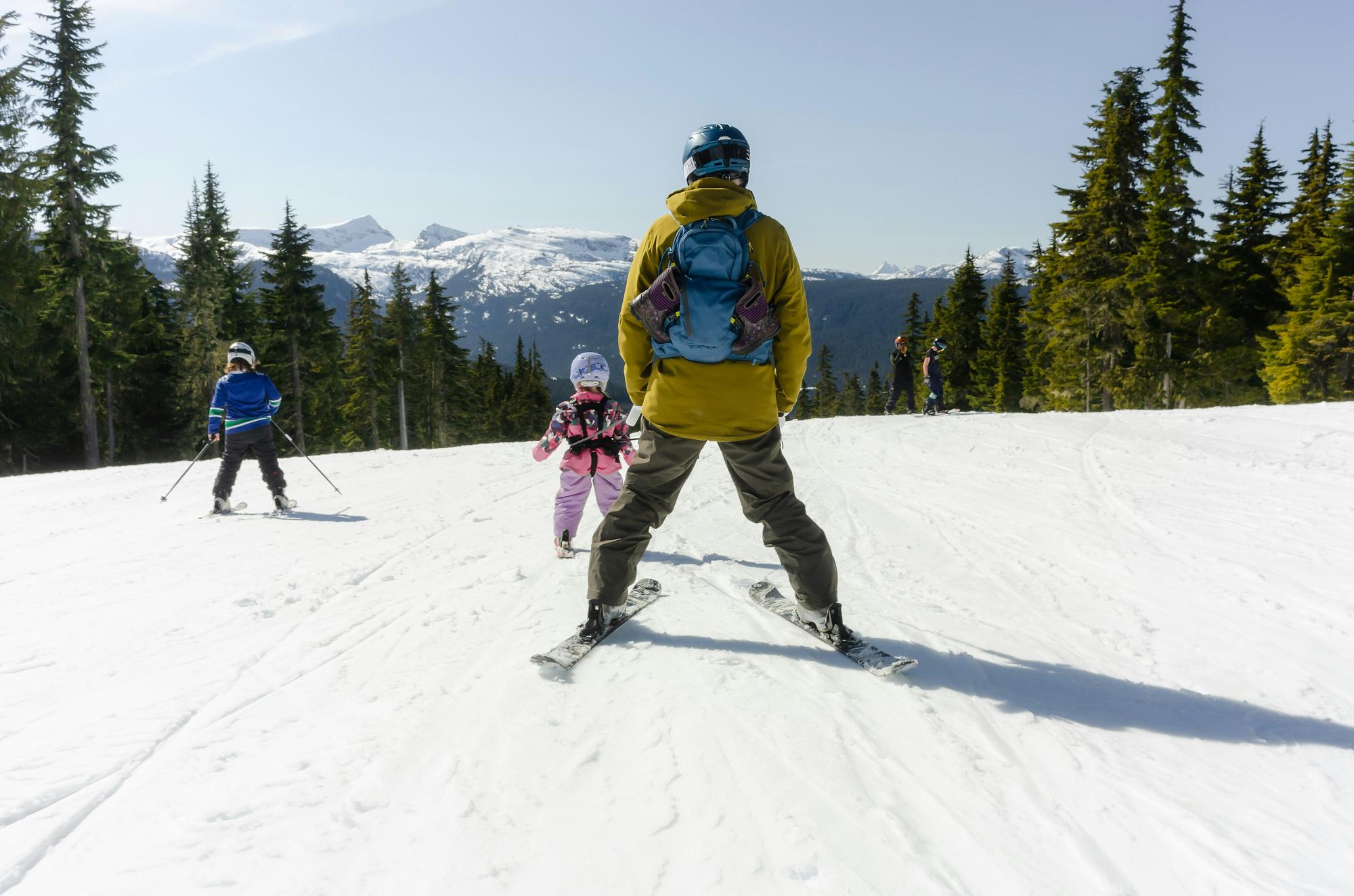 A parent and two children skiing at a family snow resort during spring break