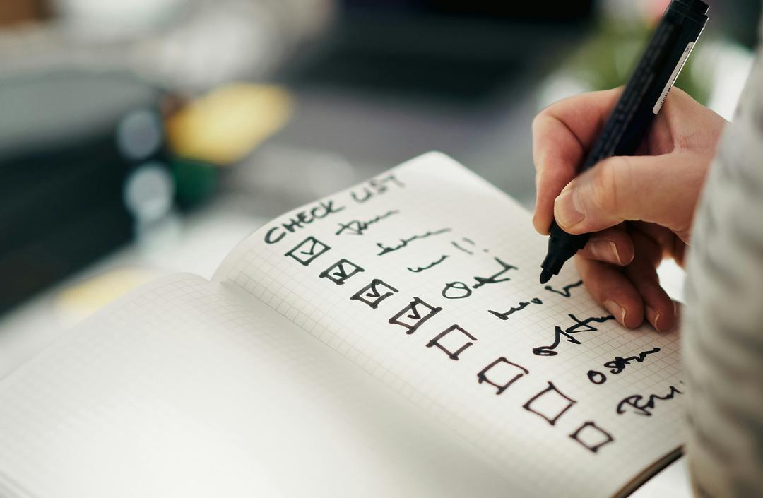 Hand checking off items on a printed shot list checklist