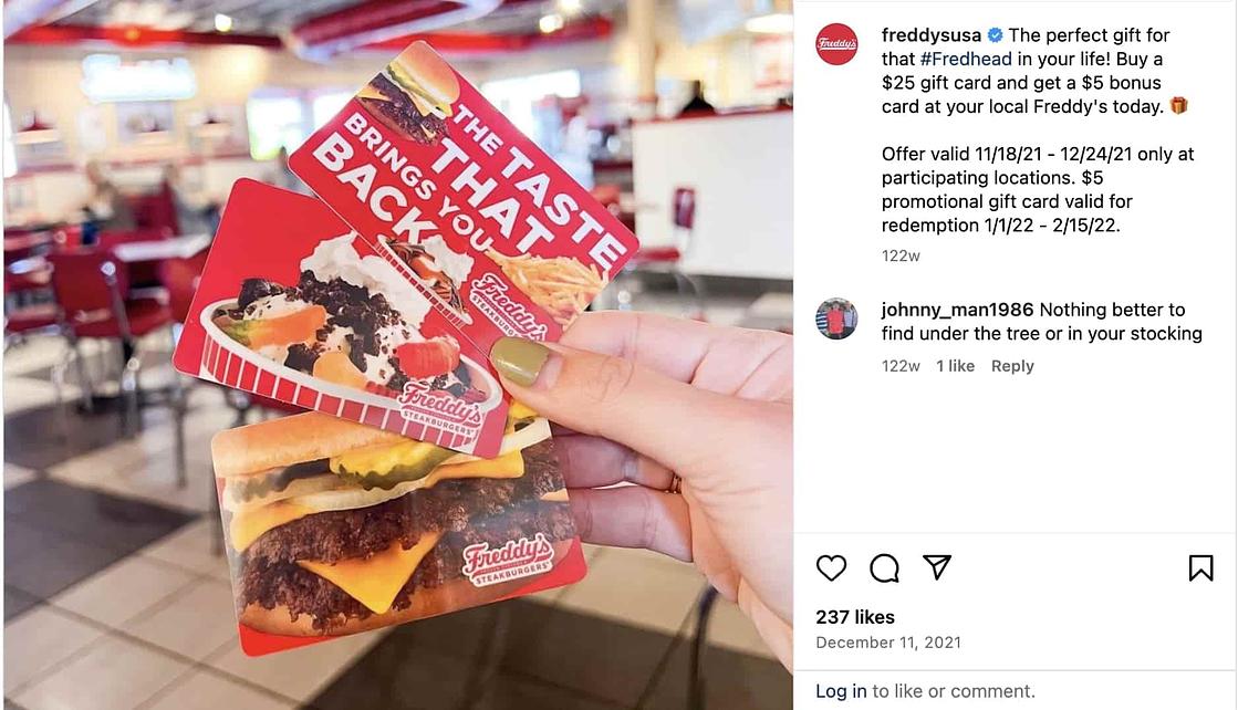 Screenshot of a hand holding three Freddy's Burger gift cards inside the restaurant.